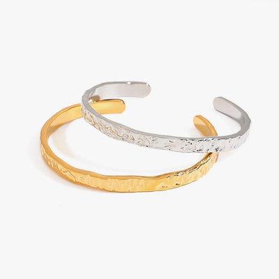 Two thin hammered open cuffs, one gold tone and one silver tone