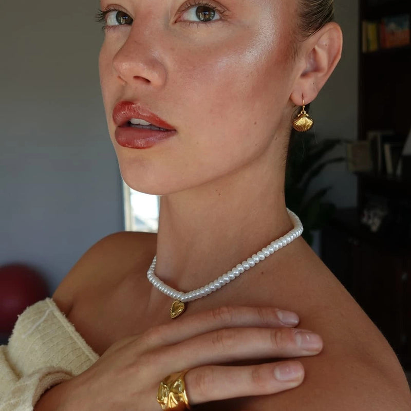 Pearl heart necklace and molten wide band ring worn together, side view