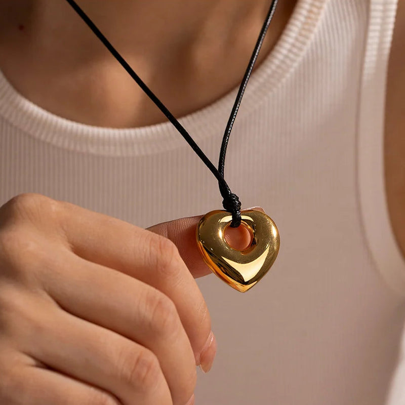 Heart cutout pendant held up on a black cord