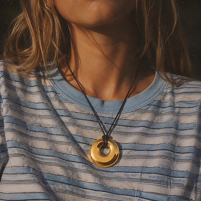Disc pendant cord necklace worn with a blue striped tee
