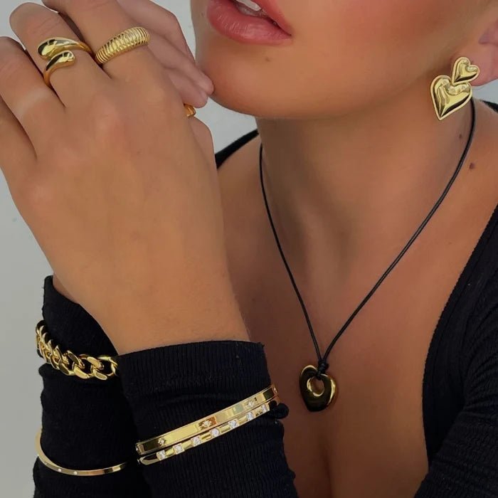 Heart cord necklace worn with stacked bracelets and rings