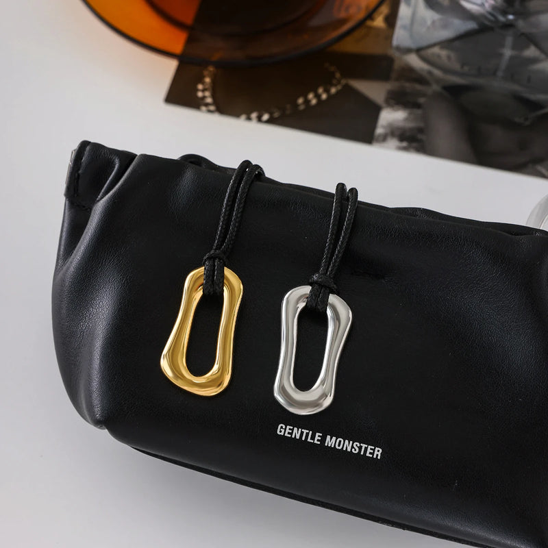 Gold and silver-tone link pendants resting on a black bag