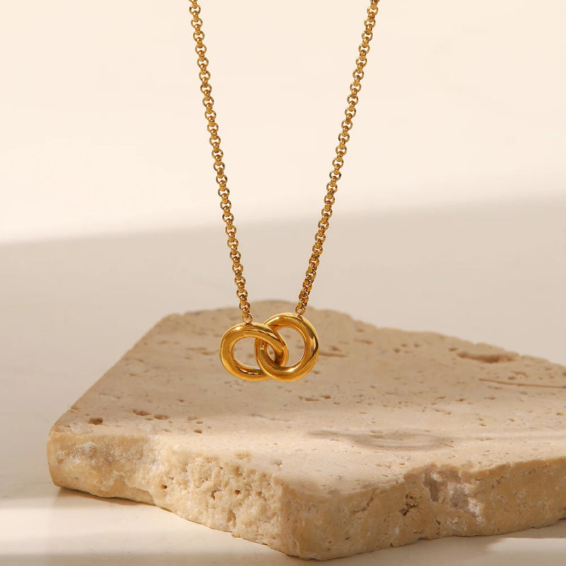Interlocking circles pendant necklace propped on pale stone