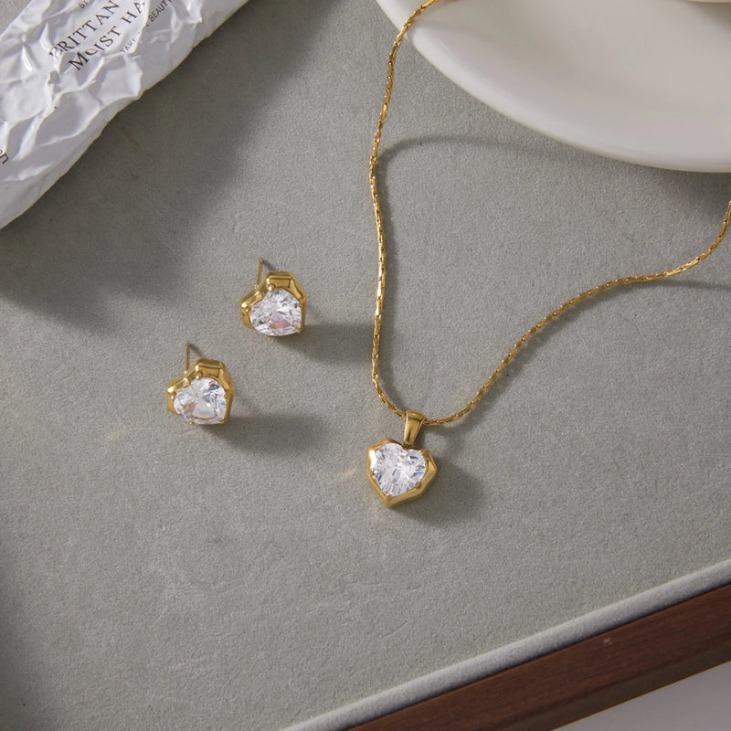 Necklace and both stud earrings laid out on a grey surface