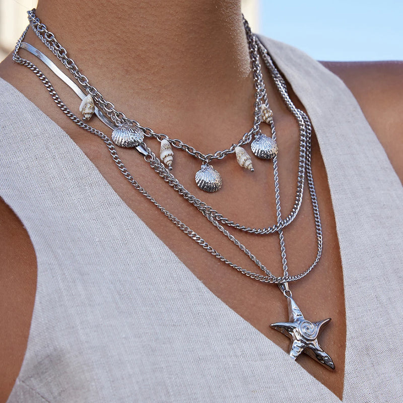 Silver-tone starfish pendant worn with layered shell charm chains
