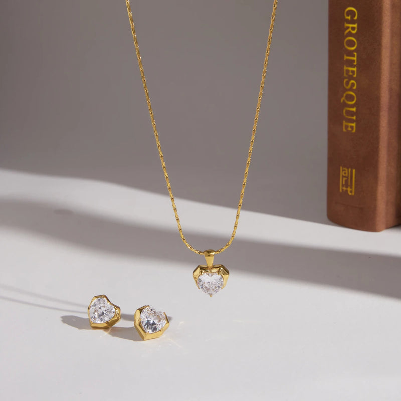 Necklace and studs arranged on a pale surface beside a book