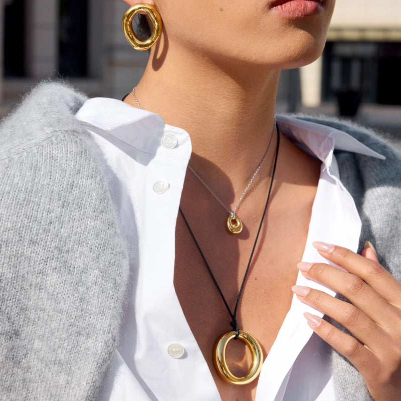 Close view of the gold-tone halo pendant on a black cord