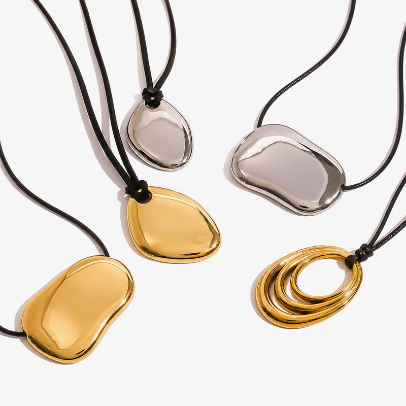 Smooth pebble pendants on black cords, in gold tone and silver tone