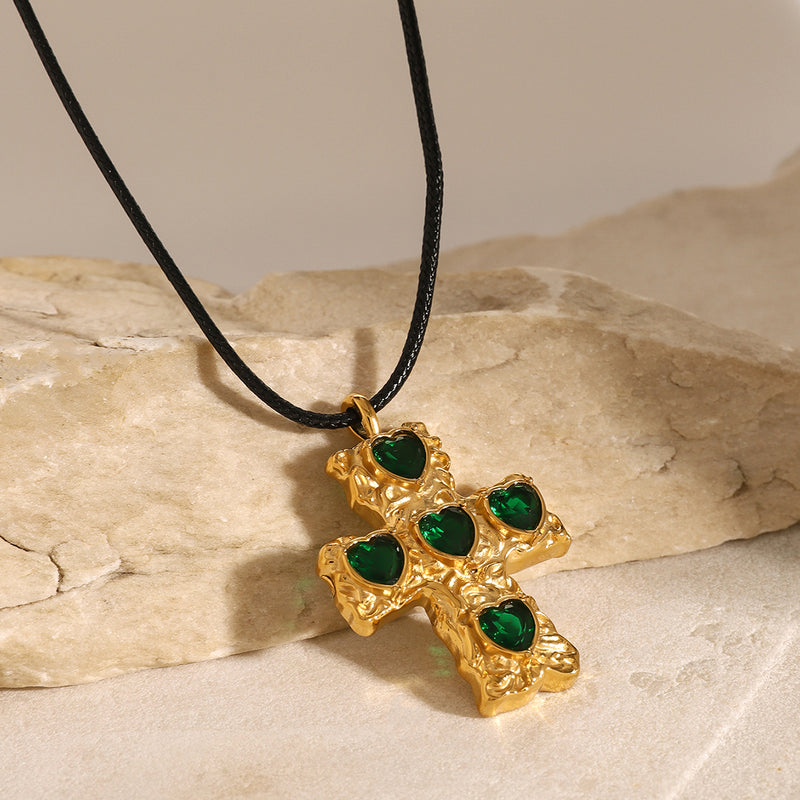 Green stone cross pendant on a cord against pale stone