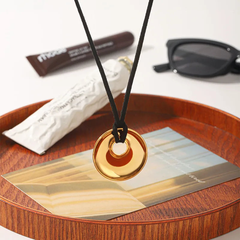 Disc pendant cord necklace on a wooden tray