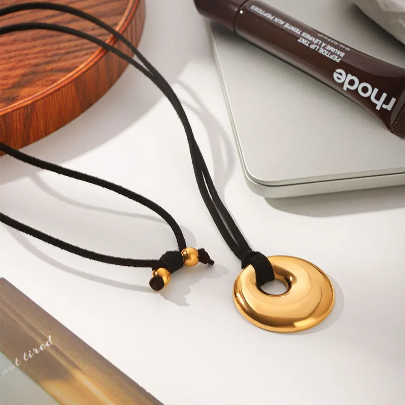 Cord necklace with a spiral disc pendant on a pale surface