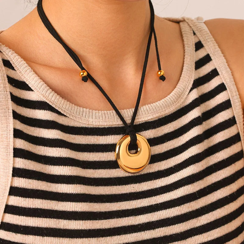 Spiral disc pendant on a cord over a striped top