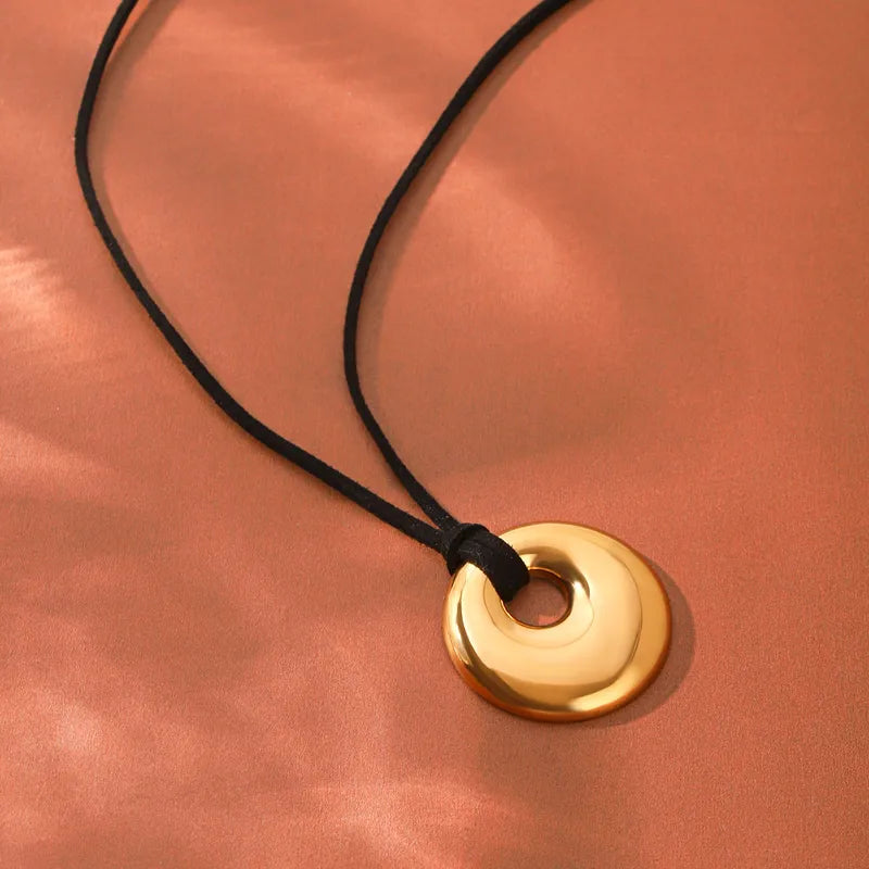 Gold-tone spiral disc pendant on a cord, orange background