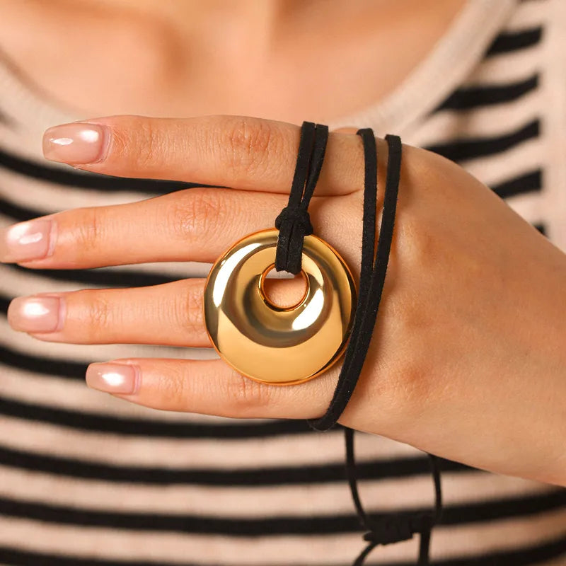 Spiral disc pendant held against the cord in a hand