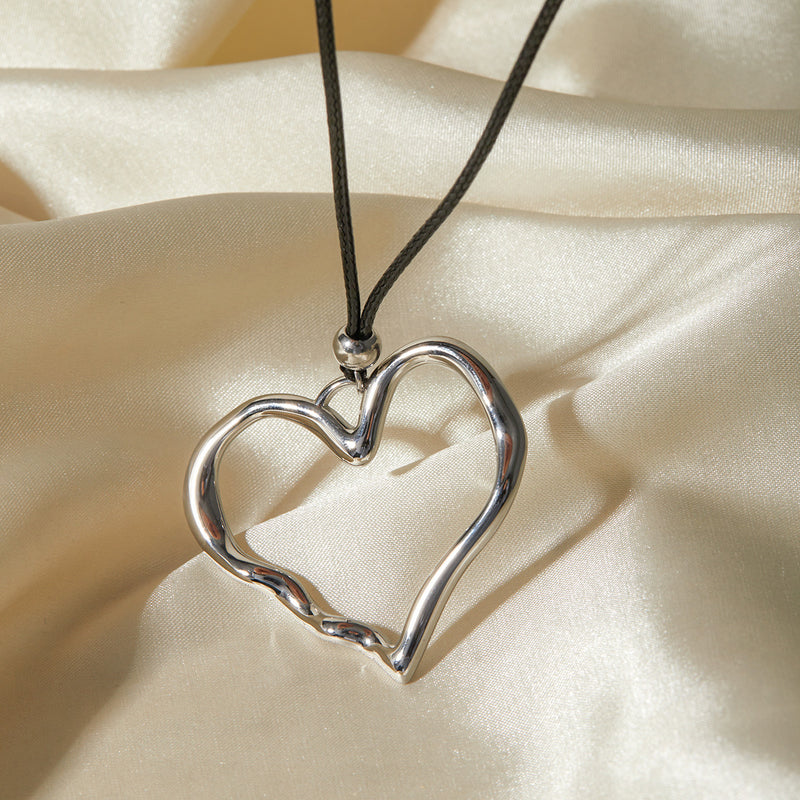 Silver-tone open heart pendant on a cord over cream satin