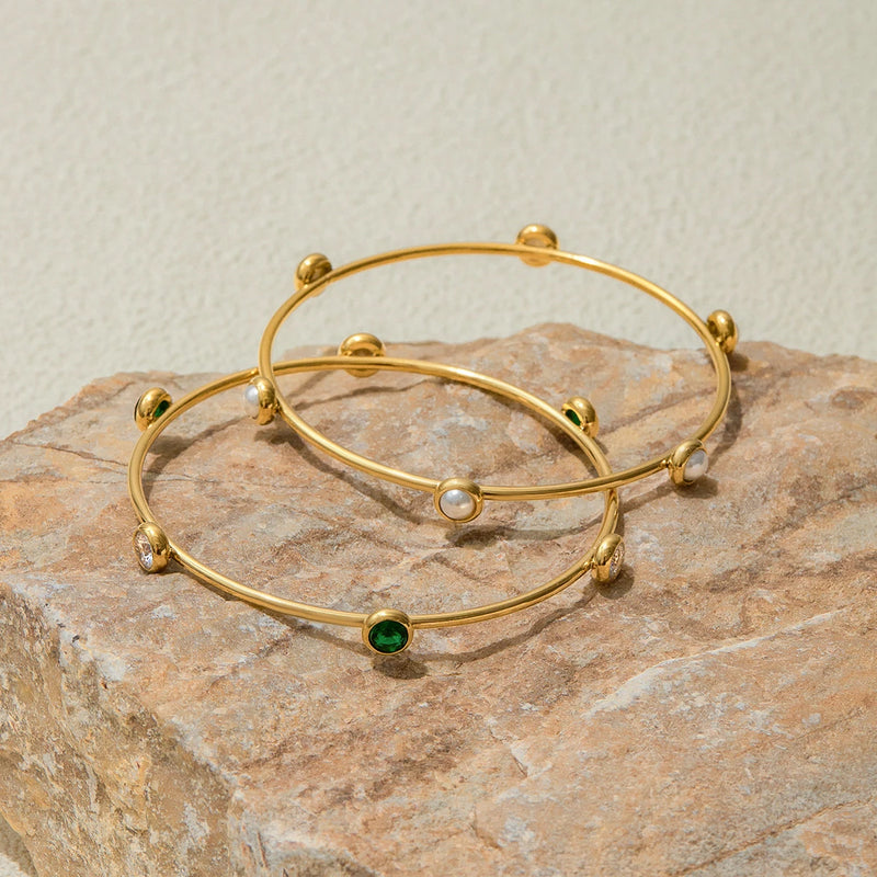 Two stone station bangles resting on a pale stone block