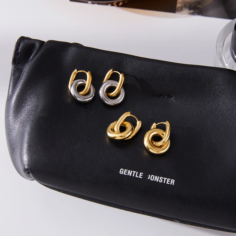 Maud Interlocking Ring Hoop Earrings, both colourways resting on a bag