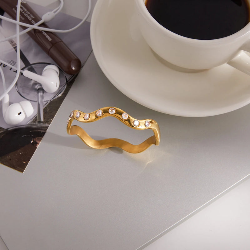 Wave bangle on a grey surface beside coffee and earphones