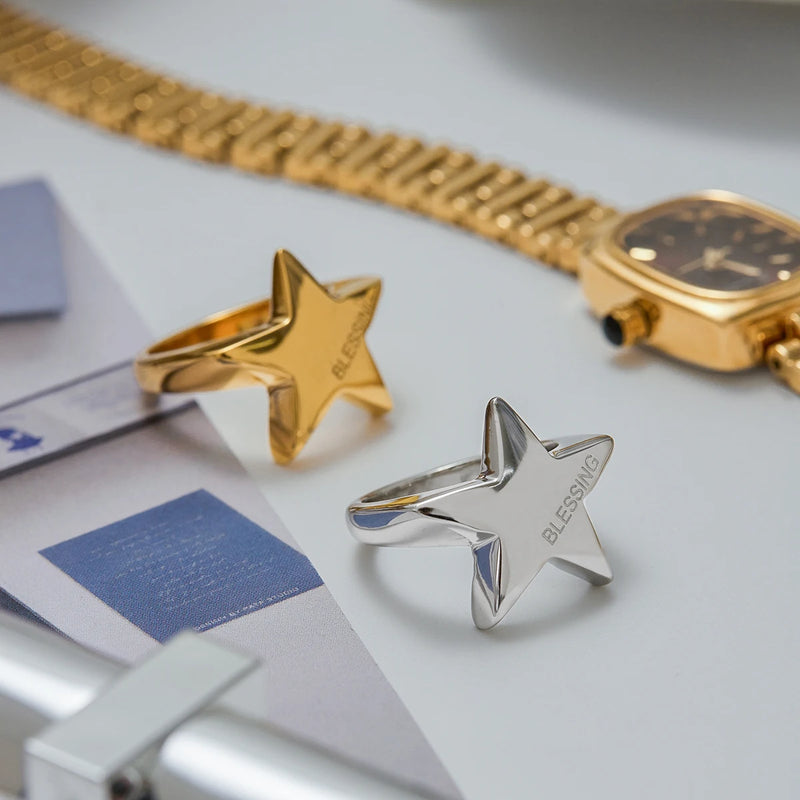Two puffed star rings on a pale surface beside a watch