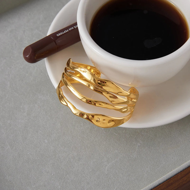 Wave cuff bangle resting against a cup of black coffee