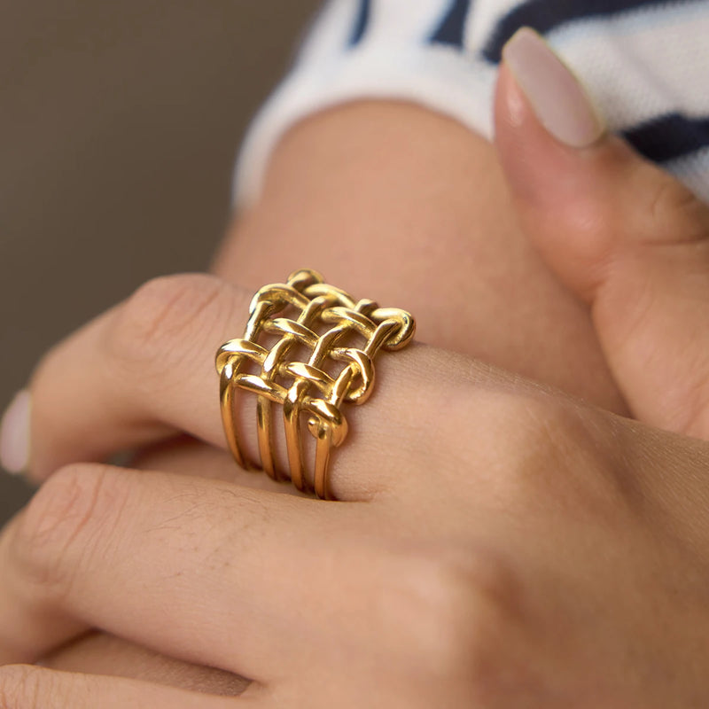 Wide gold-tone basketweave ring worn on a finger