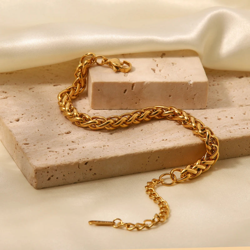 Wheat chain bracelet trailing from a pale stone block