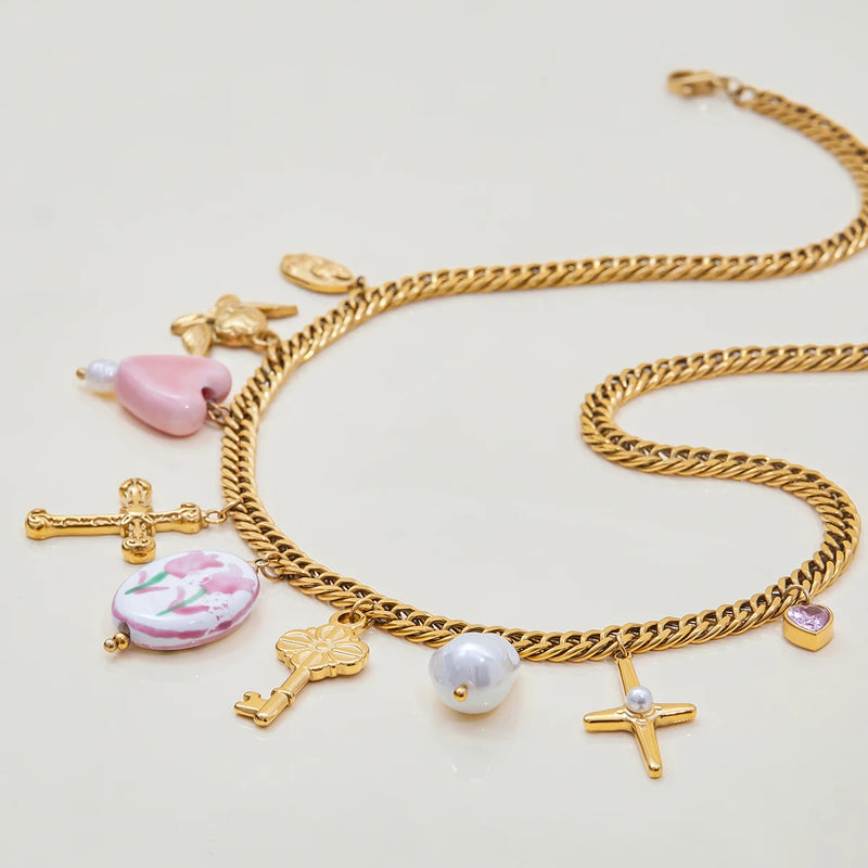 Close view of the cross, key and pastel charms on a curb chain