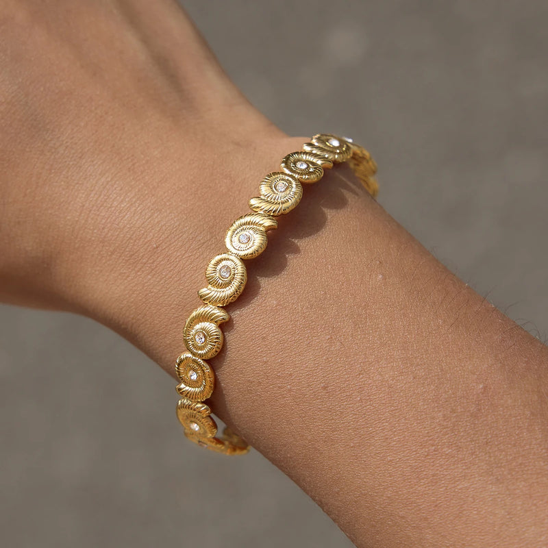 Spiral shell cuff worn on a wrist, arm outstretched