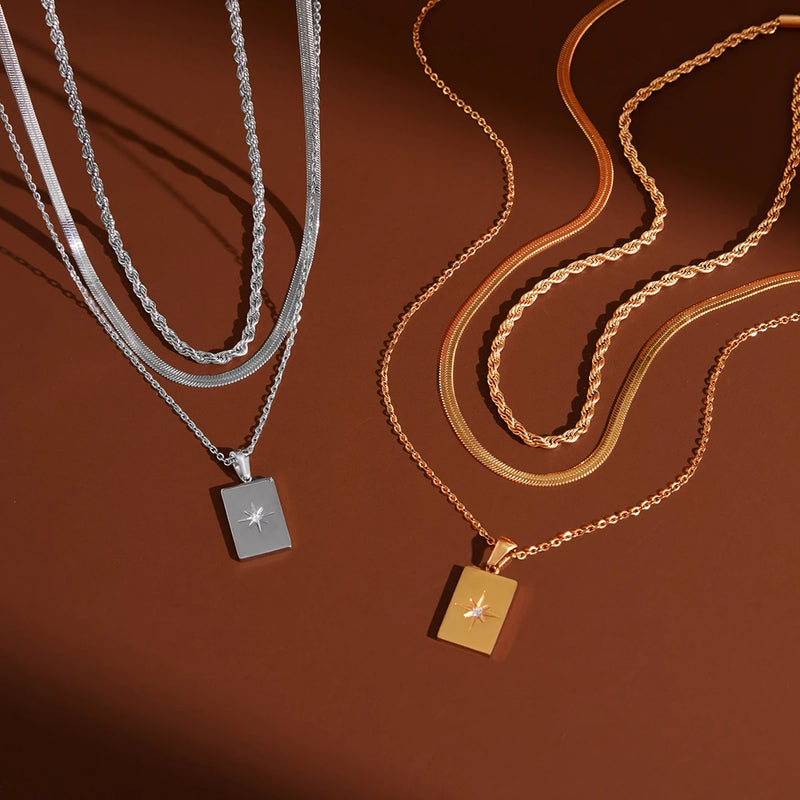 Silver-tone and gold-tone layered star tag necklaces on brown