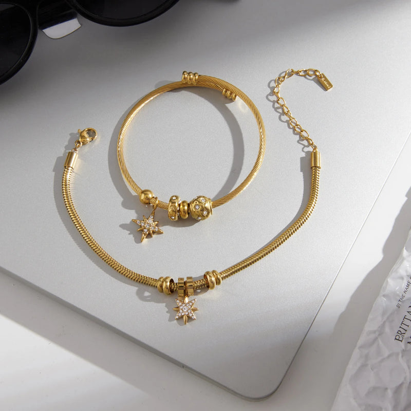 Two star charm bangles on a pale surface with an extender chain