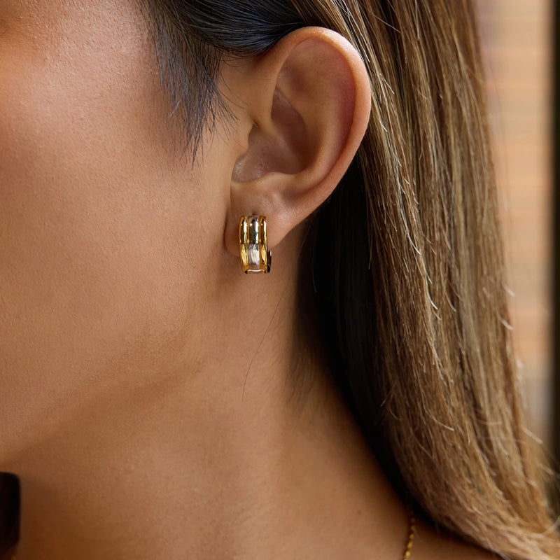 Two-tone huggie hoop earring worn on the ear, side view