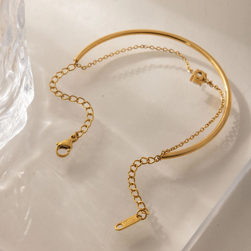 Bangle joined to a fine chain, laid on cream fabric