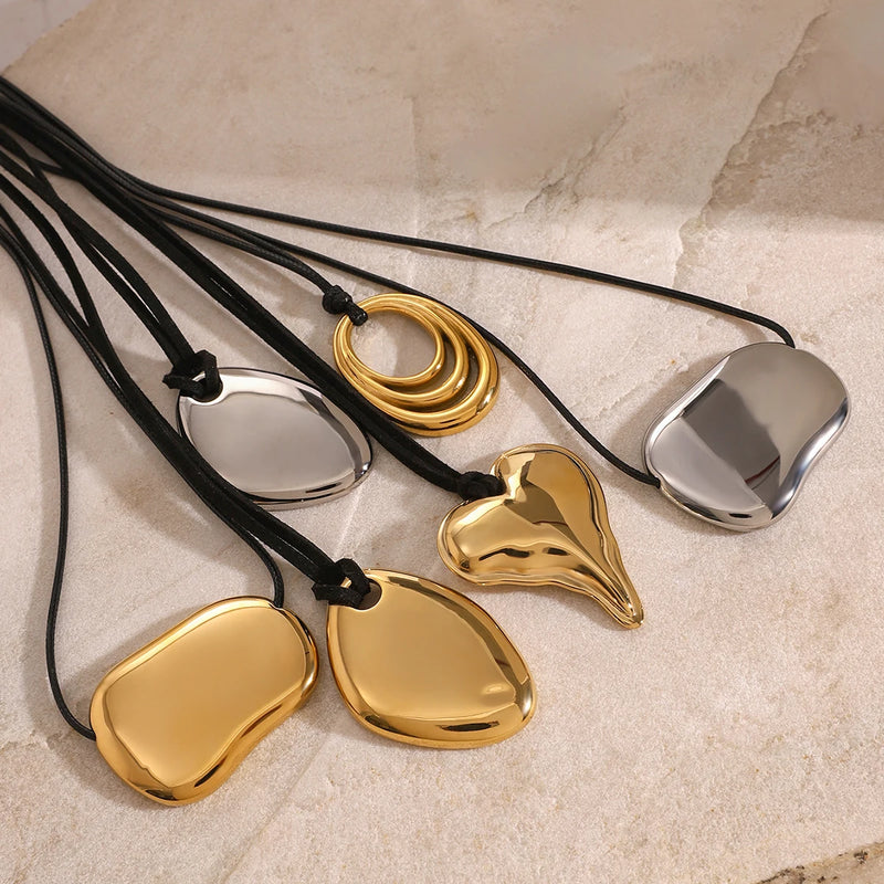 Group of pebble and heart pendant cord necklaces on cream