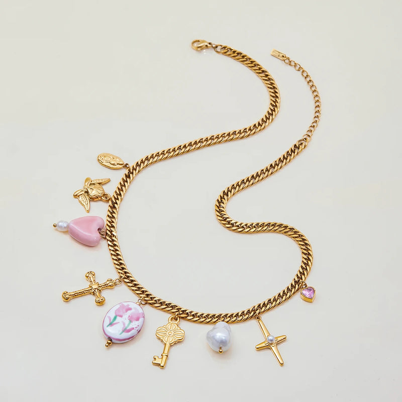 Curb chain with cross, key and heart charms on a cream surface