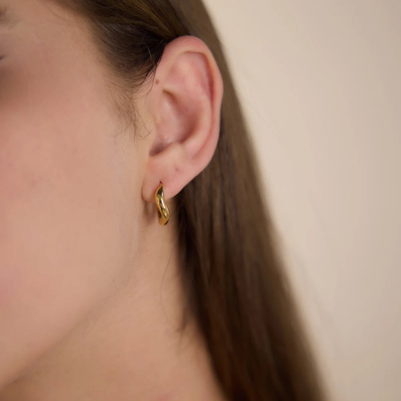 Small sculpted hoop earring worn on the ear, side view