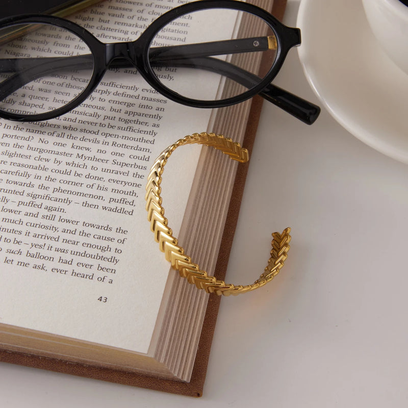 Chevron cuff resting against an open book with glasses behind