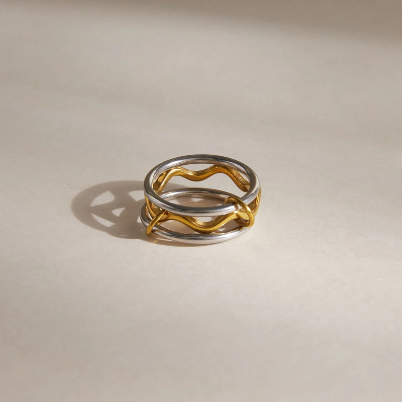 Two-tone wave ring standing on a pale surface