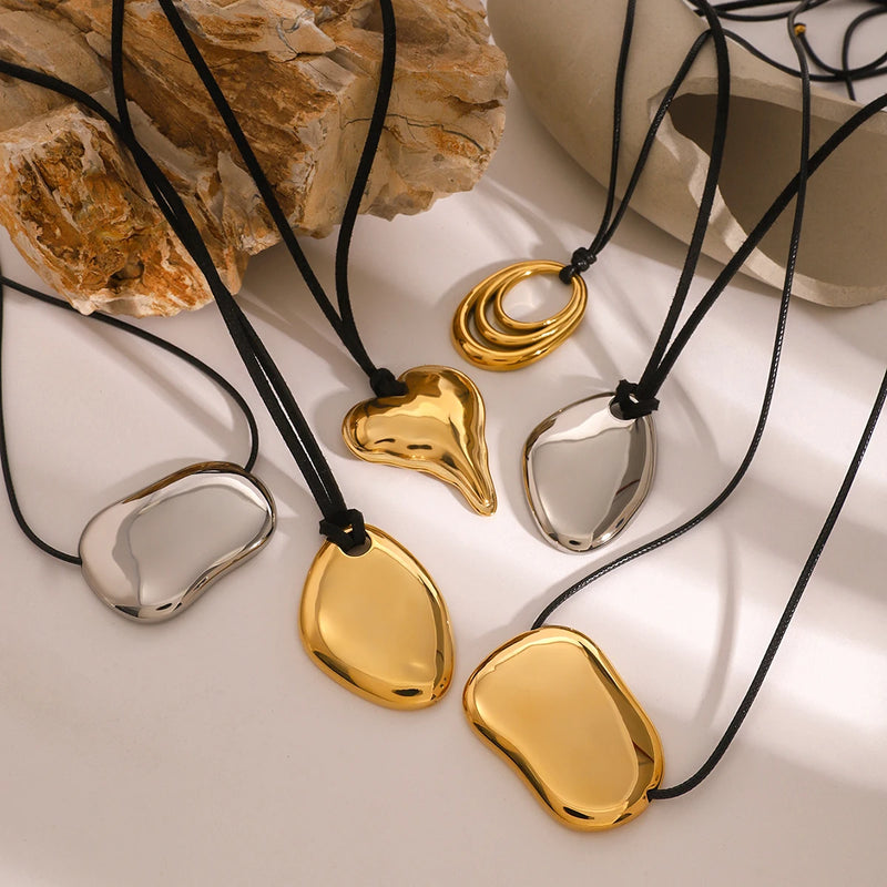 Cord necklaces with gold and silver-tone pendants on stone