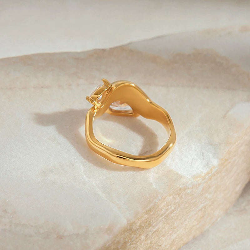 Sculptural teardrop ring seen from the side on pale stone