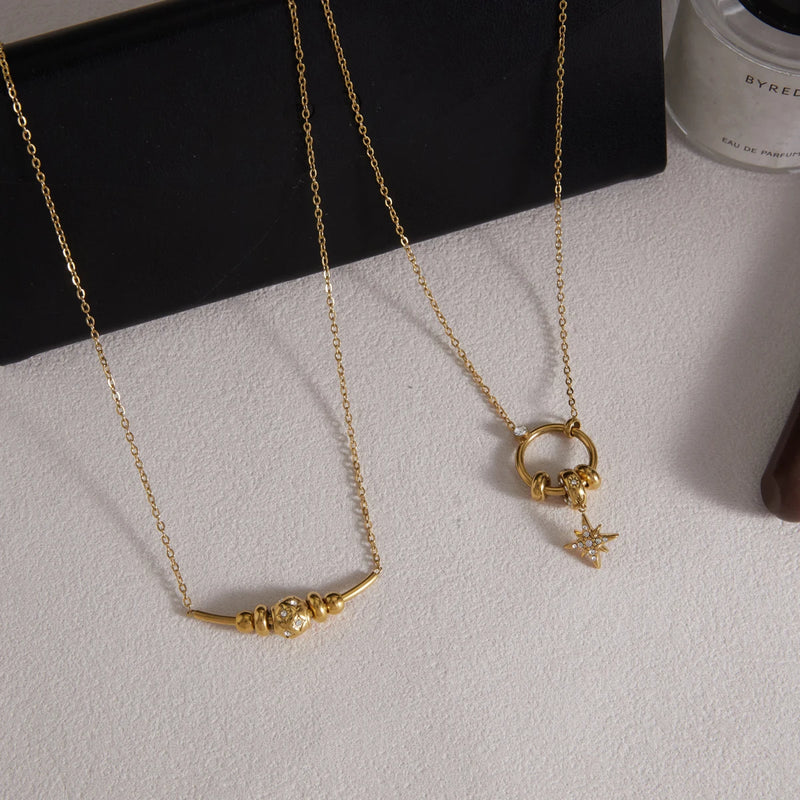 Two chain necklaces with a star drop on a pale surface