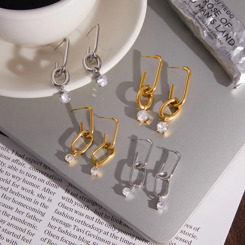 Gold and silver-tone link drop earrings laid on an open magazine