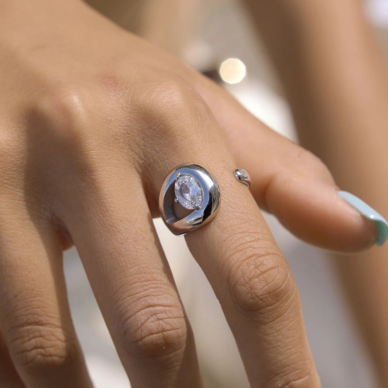 Silver-tone teardrop ring with a clear stone worn on a finger