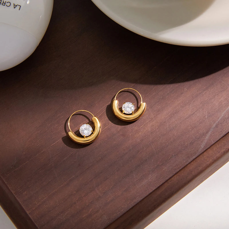 Two crescent crystal hoops on a dark wooden surface