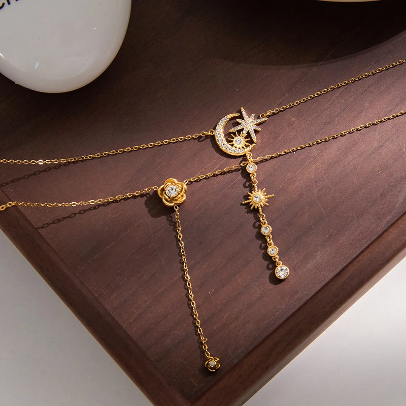 Angele Crystal Lariat Necklace on a wooden tray, star and moon charms in view