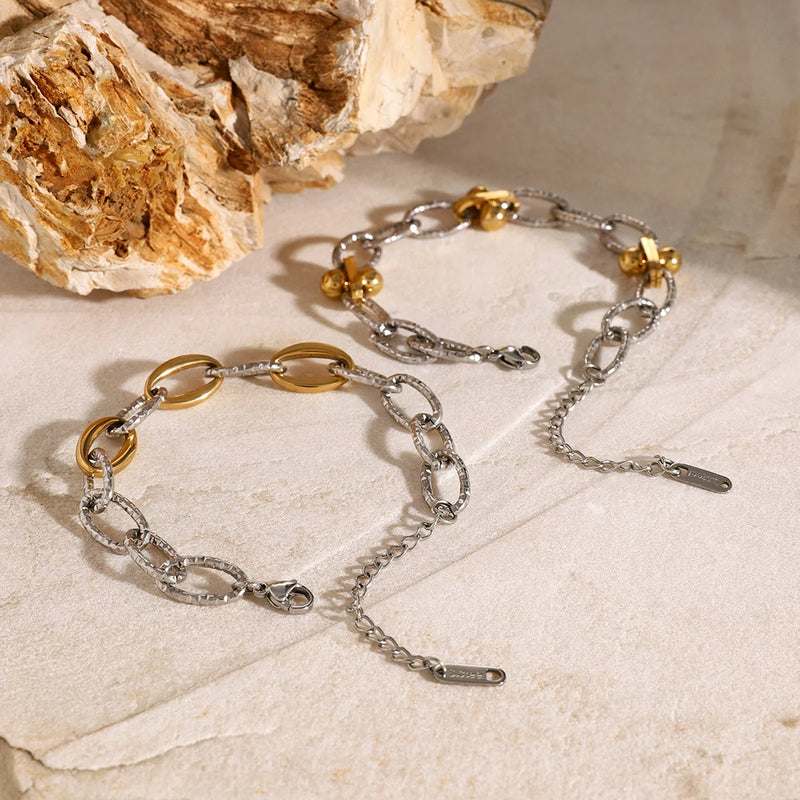 Two two-tone chain bracelets on a pale stone surface