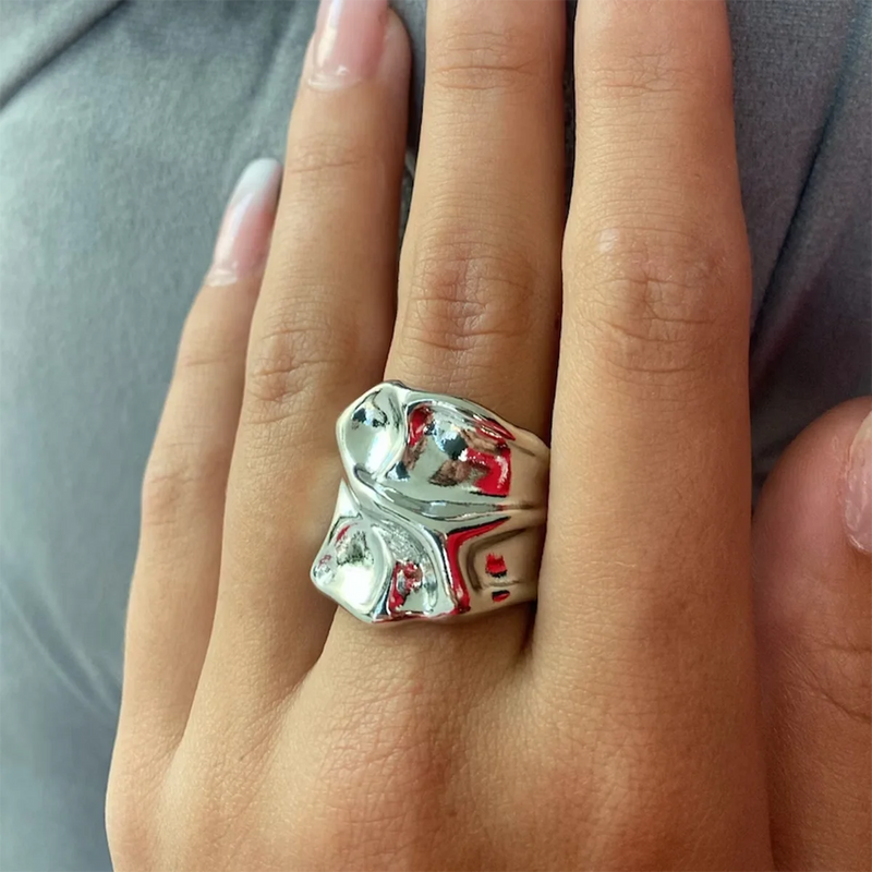Silver-tone molten band ring worn on a hand