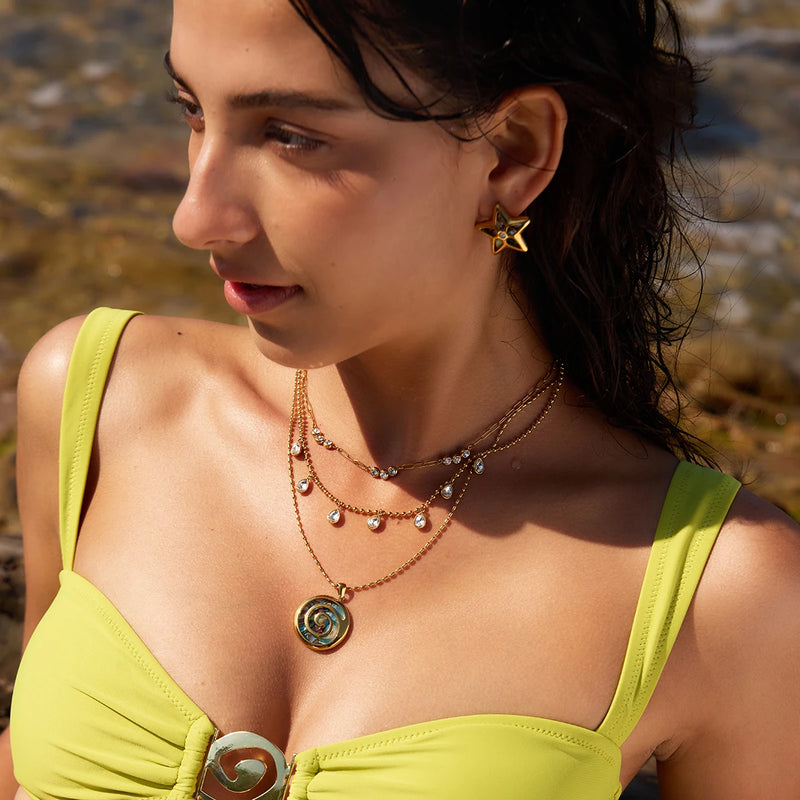 Shell spiral pendant worn layered with charm chains