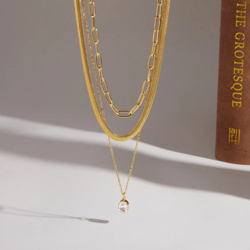Three-strand necklace on a cream surface beside a book
