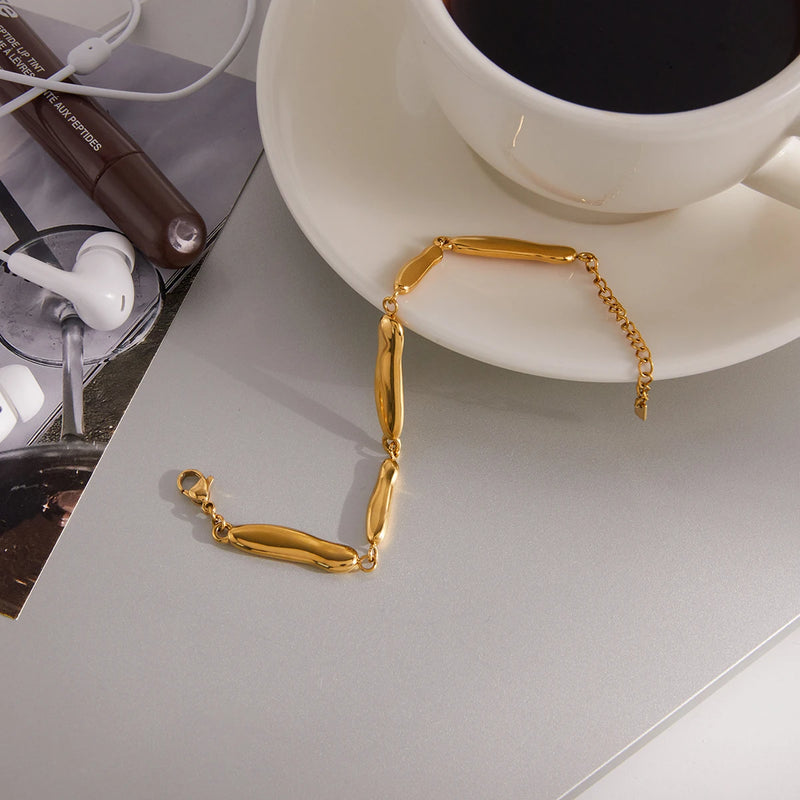 Pebble link bracelet on a grey surface beside a cup and saucer