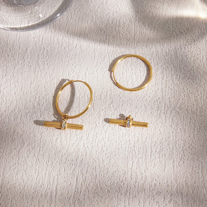 Pair of T-bar hoop earrings on a cream fabric surface